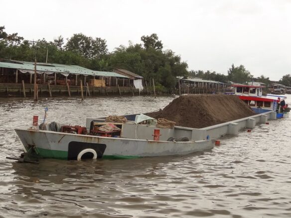 "Dredge spoils" A boat rides low in the water hauling dredged dirt from the Mekong river delta in Vietnam (by program monkey CC BY-NC-ND 2.0 via Flickr).