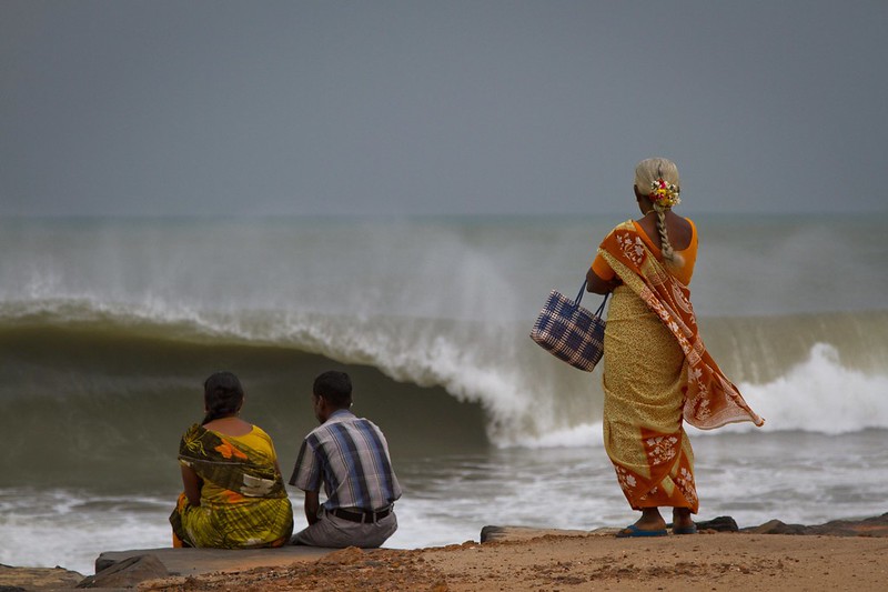 "Lady and couple watching waves" Puducherry, India (by Kate Fisher, CC BY-NC-ND 2.0 via Flickr).