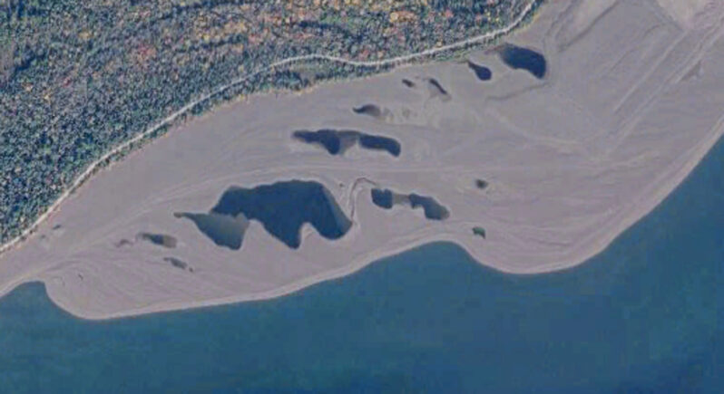 Figure 11. The distinct active Spit feature has formed on the downdrift end of one of the widest areas of the stamp sand beach which acts as a headland. Longshore beach drift around the point forms the growing spit at intervals from oldest (right) to youngest (left). The head of the spit ultimately attaches to the beach it fronts with trapped ponds forming between the “fingers.” The ponds near the road in upper right part of the image are from an earlier spit’s development. Spit formation/attachment is one way in which the beach mass widens. (Enlargement from Figure 2).