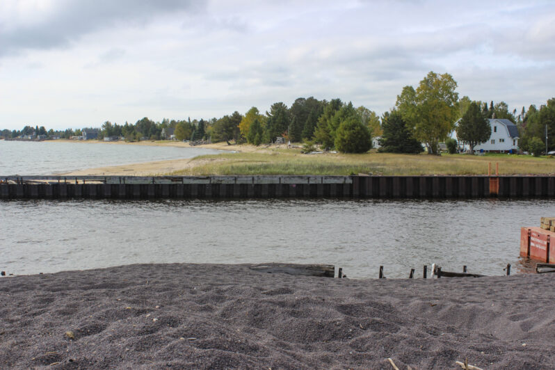 Figure 14. Foreground is stamp sand surface of the buildup behind the north jetty. Beyond the river mouth is the natural beach, widened and vegetated with grasses next to the south jetty indicating some seasonal sand transport to the north. A healthy stand of trees and village houses with recreation amenities are what could have lined the entire shoreline from here to Gay.
