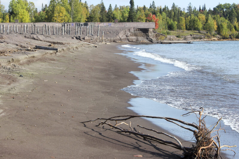 Figure 7. Eroding shoreline (2024) undercutting a segment of the concrete sluice tunnel (slime slurry) and exposing the formerly buried support posts of one of the old conveyor belts (stamp sand transport).
